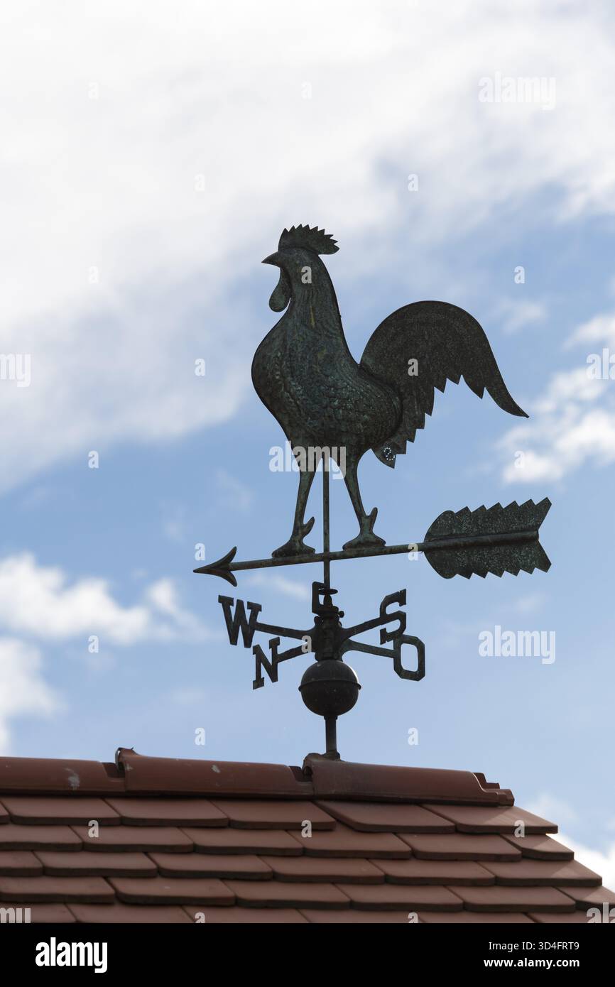 Eine dunkle Wetterfahne auf einem Dach vor blauem Himmel mit Wolken, Baden-Württemberg, Deutschland Stockfoto