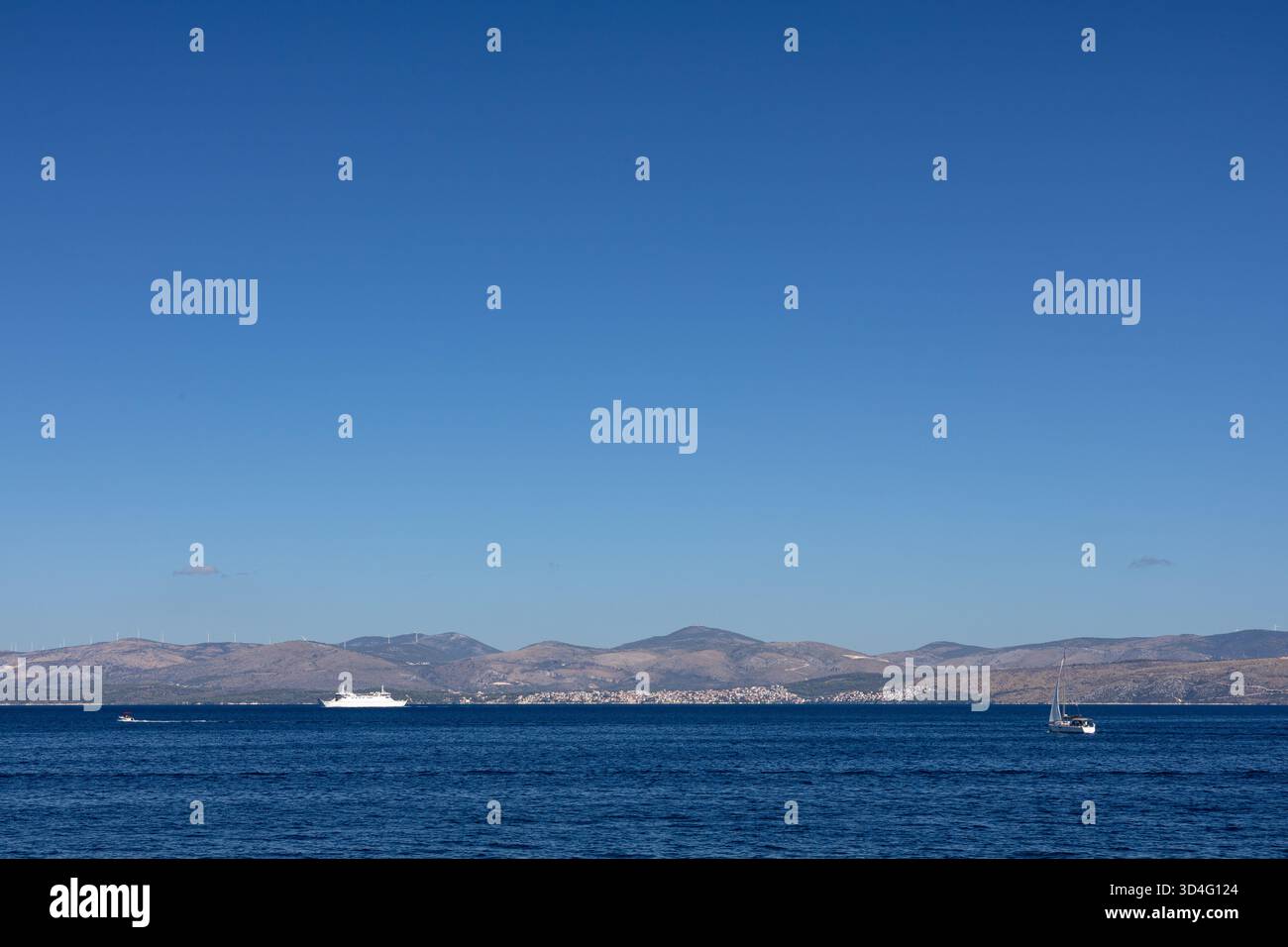Ein klarer blauer Himmel trifft auf ein ruhiges Meer mit kleinen Booten, während sich entfernte Hügel am Horizont erheben. Perfekt für Reisen, Urlaub und Natur ima Stockfoto