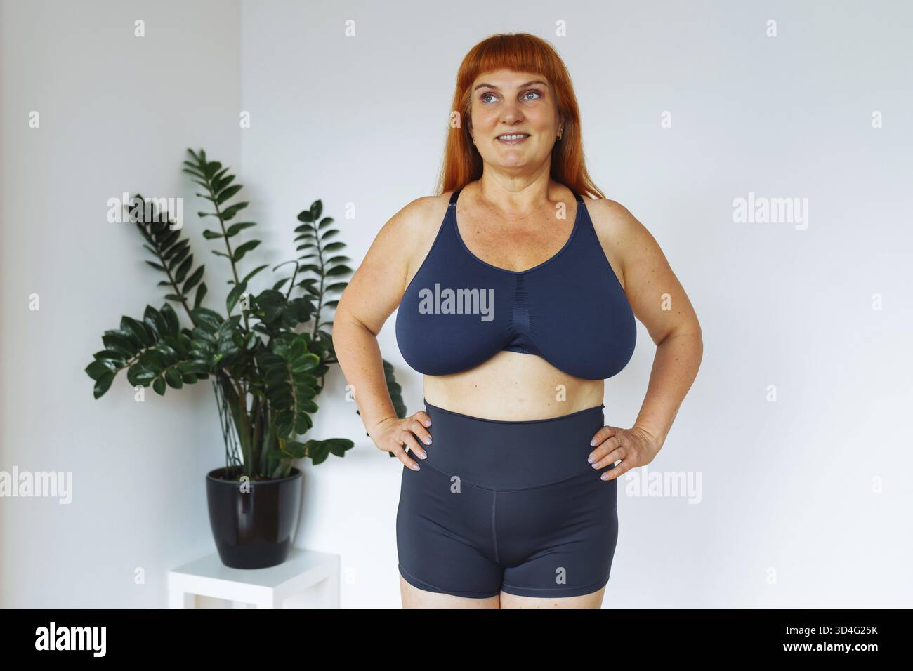 Positive ältere Frau macht Übungen, macht Krafttraining zu Hause Workout zu Hause, freien Platz. Eine reife Frau in einem Sporttop, Shorts, kurvig, le Stockfoto
