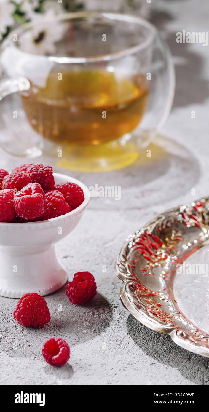 Essen, Himbeeren in einer Schüssel und eine Tasse Tee Stockfoto