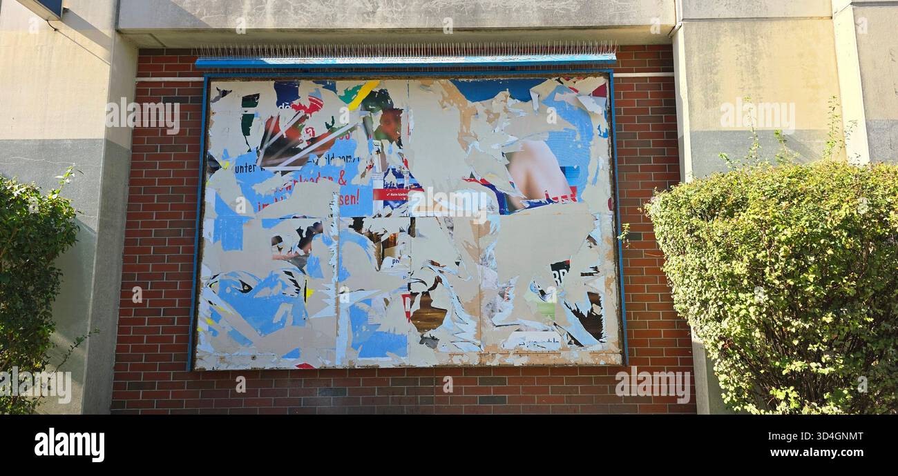 Urban Wall zeigt abblätternde Poster in lebhaften Farben, die ein abstraktes Kunstwerk mit strukturierten Schichten und urbaner Atmosphäre schaffen. - Smartphone-aufgenommenes Stockfoto