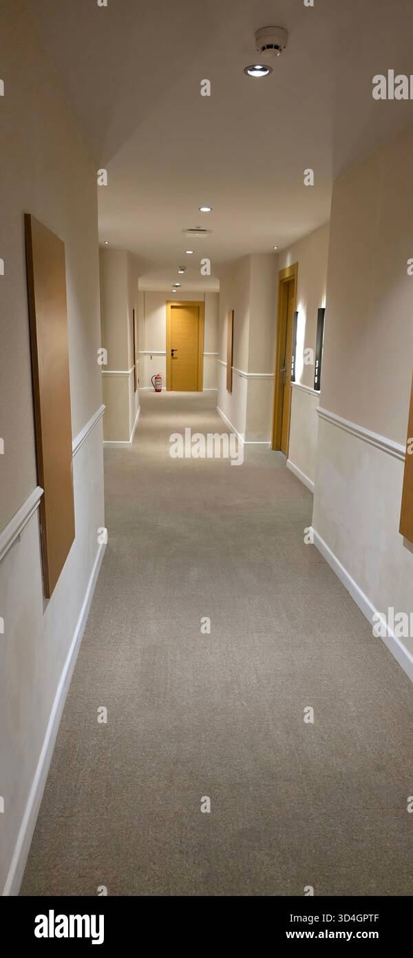 . Langer Korridor in einem Hotel mit Türen auf beiden Seiten und sanfter Beleuchtung, die eine einladende und ruhige Umgebung für Gäste schaffen Stockfoto