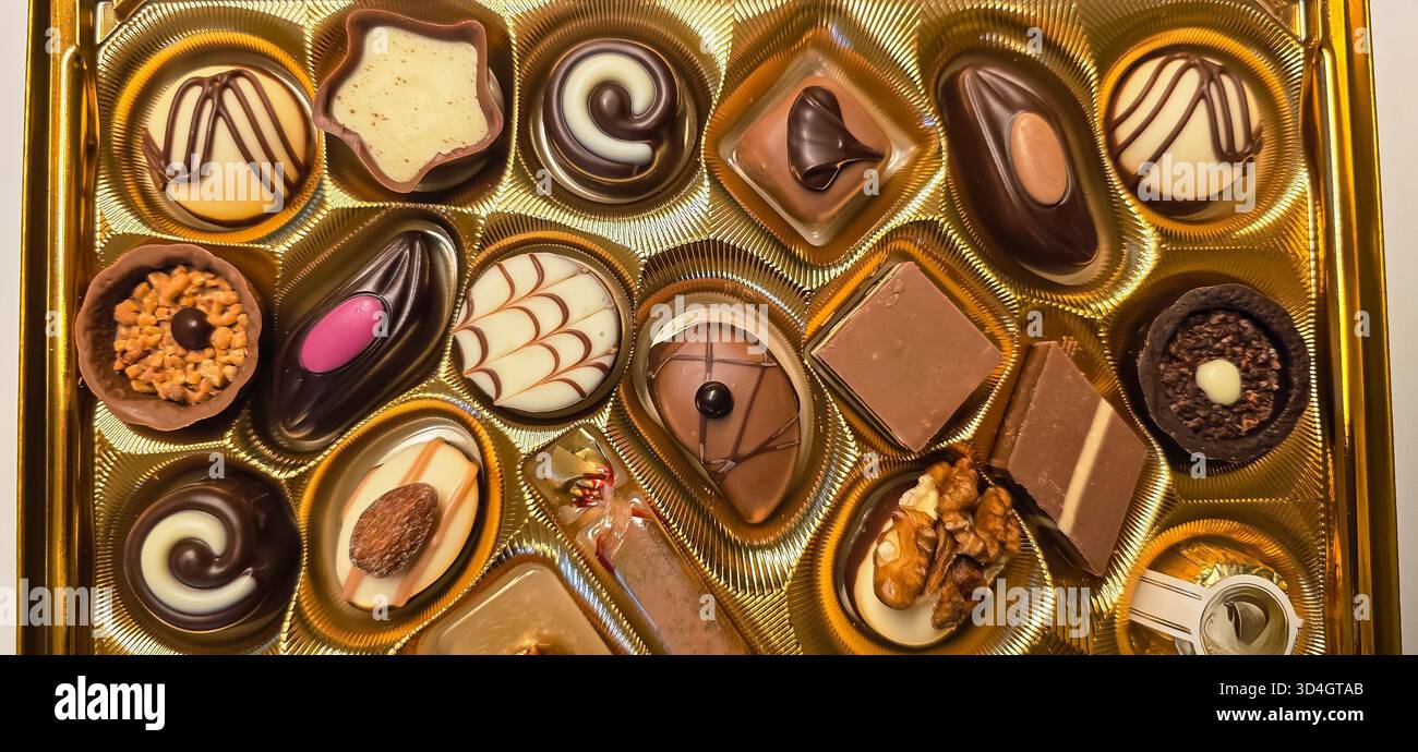 Verschiedene Gourmet-Pralinen in einer eleganten Goldbox mit verschiedenen Formen und Texturen, perfekt für köstliche Leckereien oder Geschenke. - Smartphone-aufgenommenes Stockfoto