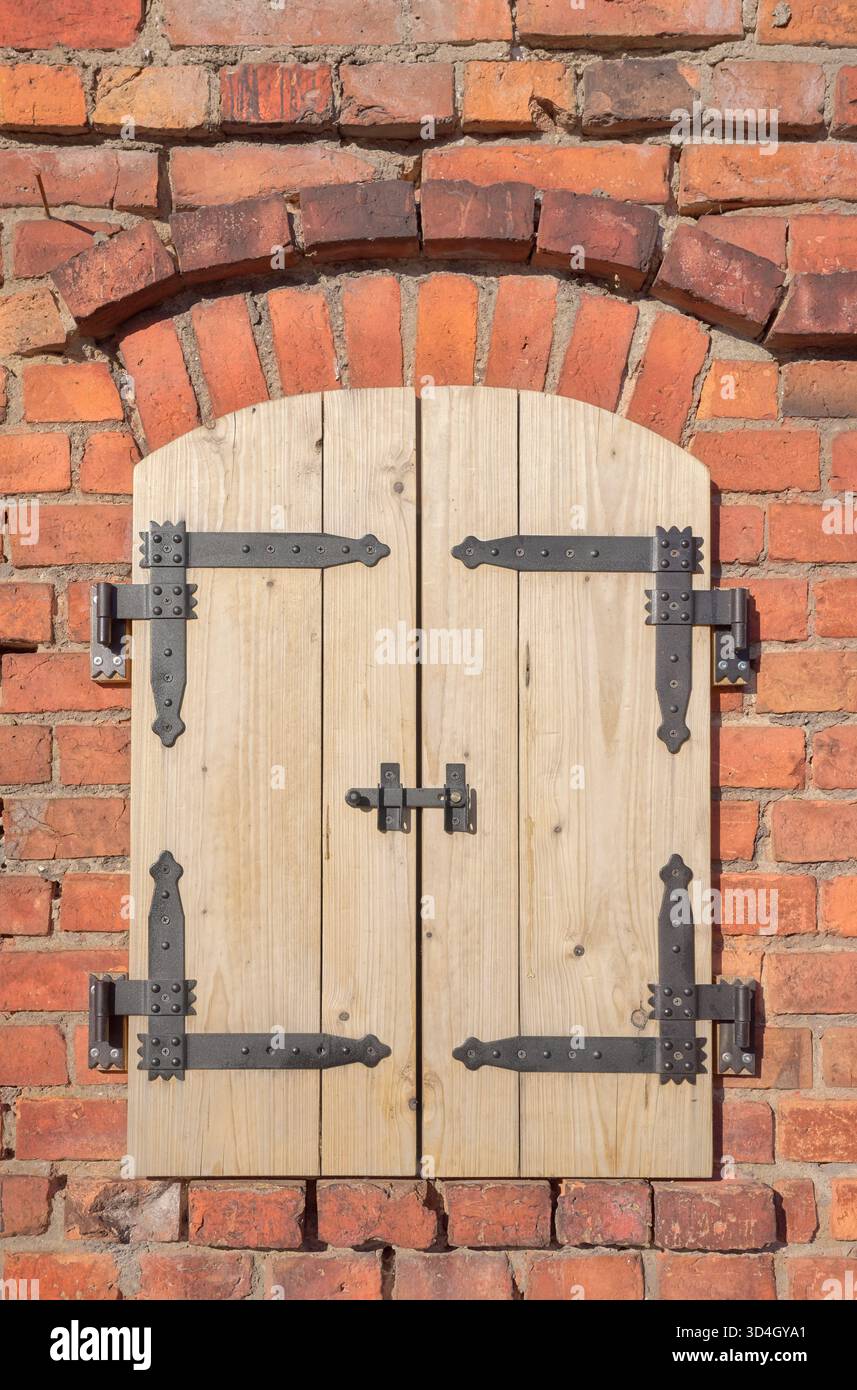 Alte Ziegelmauer mit neuen Holzläden. Stockfoto