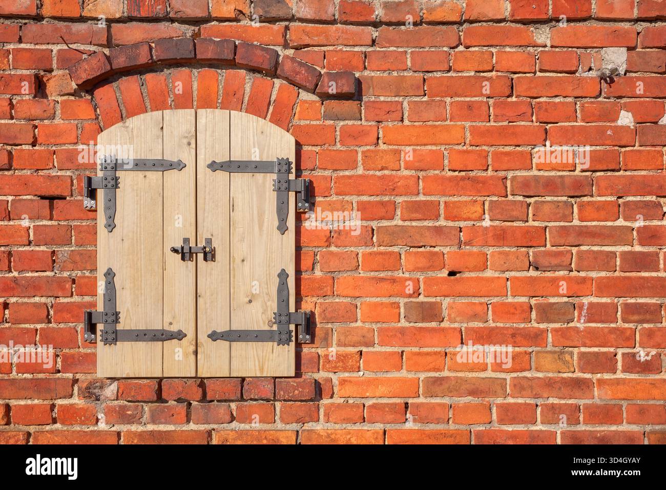 Alte Ziegelmauer mit neuen Holzläden. Stockfoto
