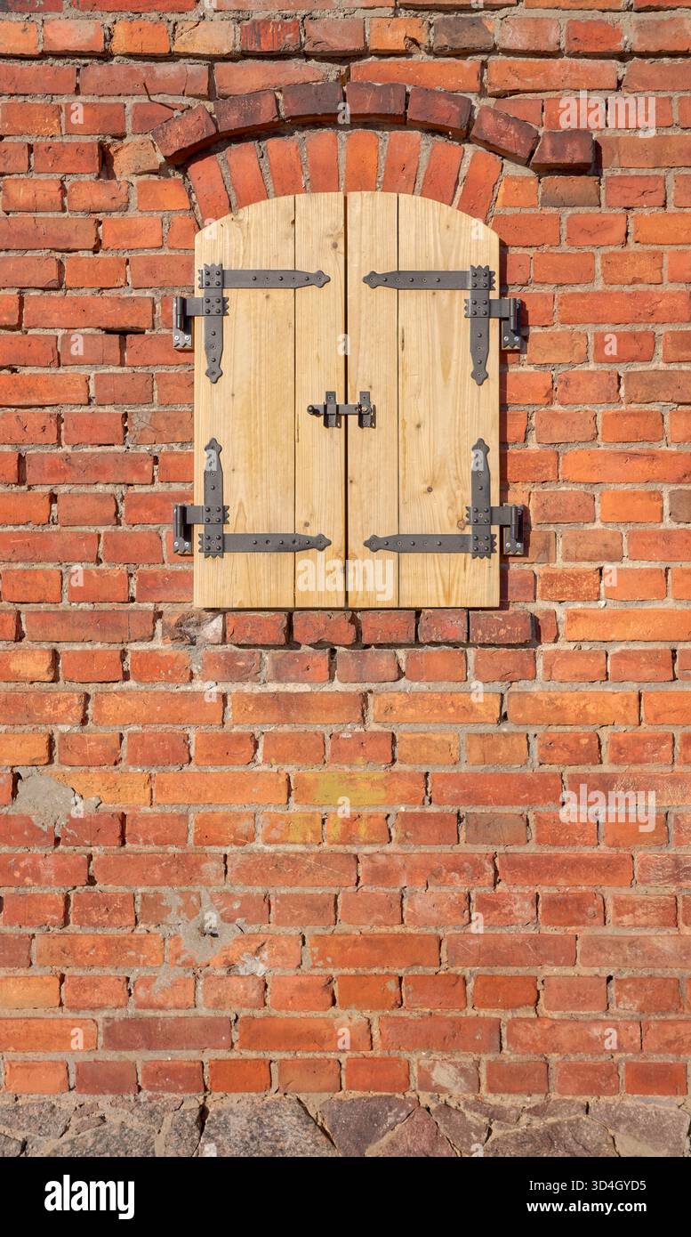 Alte Ziegelmauer mit neuen Holzläden. Stockfoto