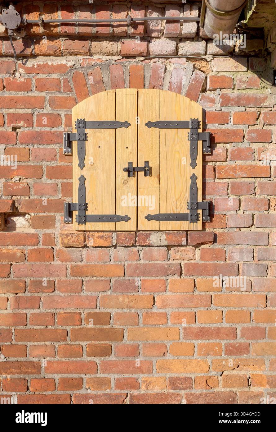Alte Ziegelmauer mit neuen Holzläden. Stockfoto