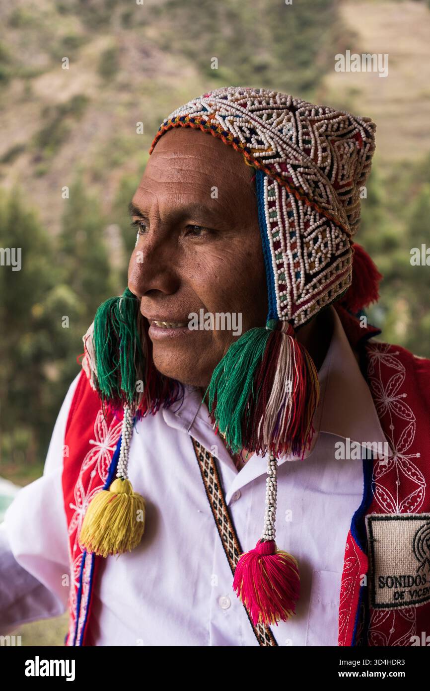 Porträt eines Quechua-Handwerkers aus Pisac, Peru, der traditionelle Andenkleidung mit farbenfrohen gewebten Details trägt. Stockfoto