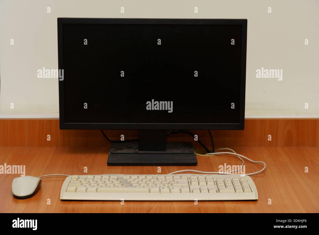 Ein Computer steht leise auf einem Holzschreibtisch mit Monitor, Tastatur und Maus und ist bereit für den Einsatz in einem Büro. Stockfoto