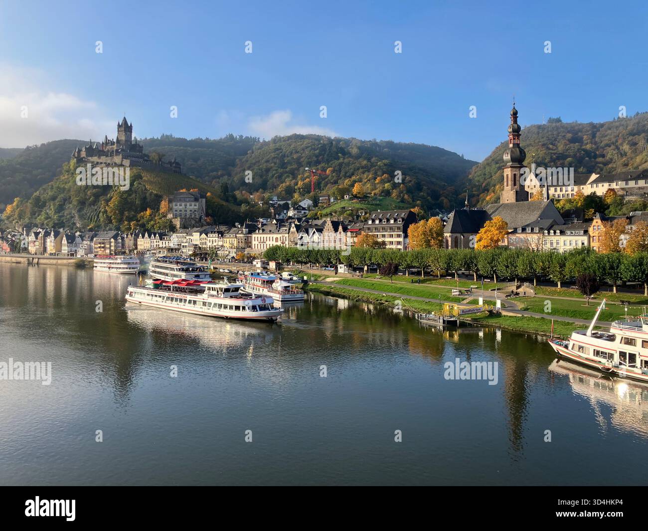 Panoramablick auf Cochem entlang der Mosel mit der Reichsburg auf dem Hügel und Passagierschiffen auf dem Wasser. Deutschland. Stockfoto
