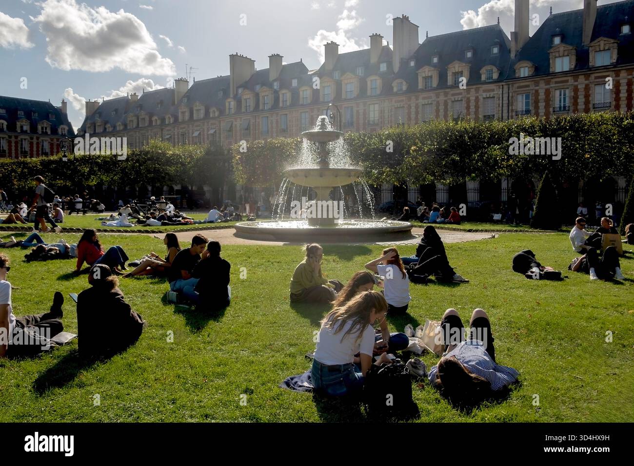 Menschen, die die Sonne genießen, am Place des Vosges, Marais, Paris, Frankreich Stockfoto