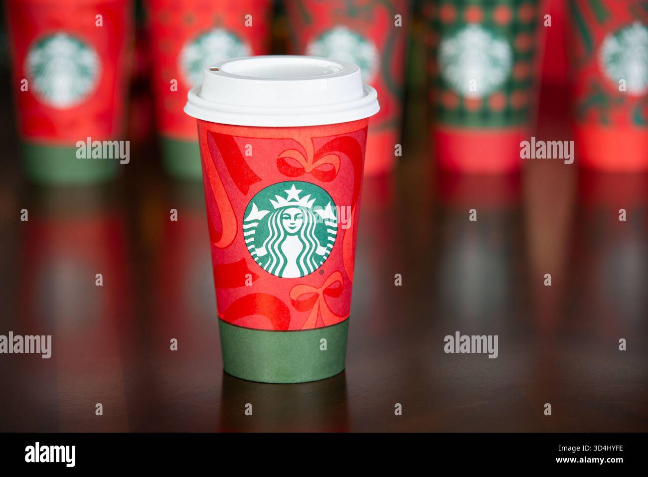 Dallas, Texas - 9. November 2025: Nahaufnahme des Starbucks Drinks im neuen festlichen Weihnachtsbecher 2025. Eine Reihe von Weihnachtsbechern im Hintergrund. Stockfoto