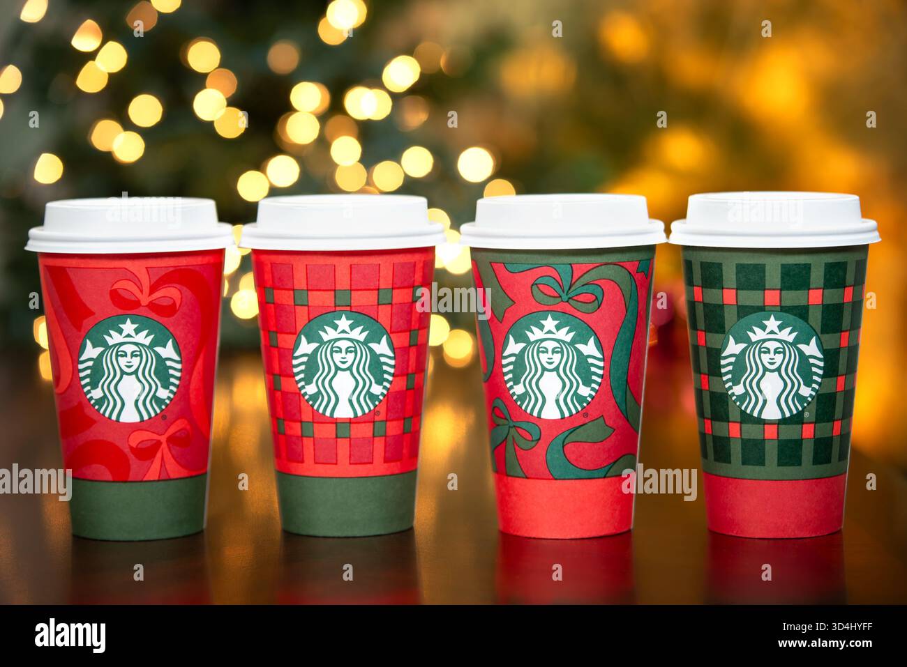 Dallas, Texas - 9. November 2025: Eine Reihe von Starbucks-Getränken in den neuen 2025 gestalteten festlichen Bechern. Weihnachtsbeleuchtung Hintergrund. Stockfoto