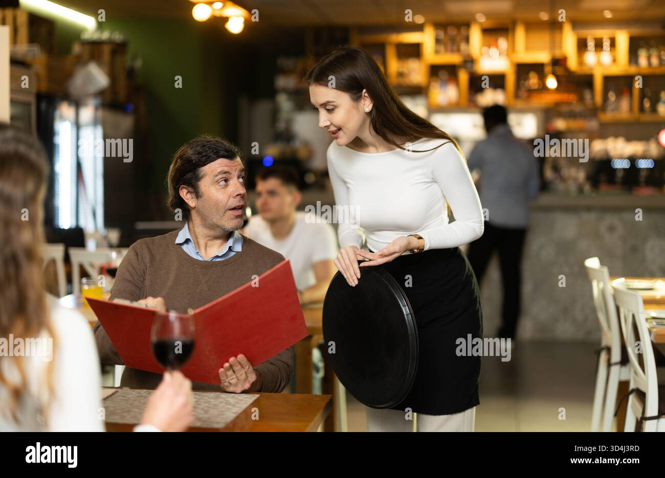 Mann, nachdem er die Speisekarte gelesen hat, bestellt er die Kellnerin Stockfoto