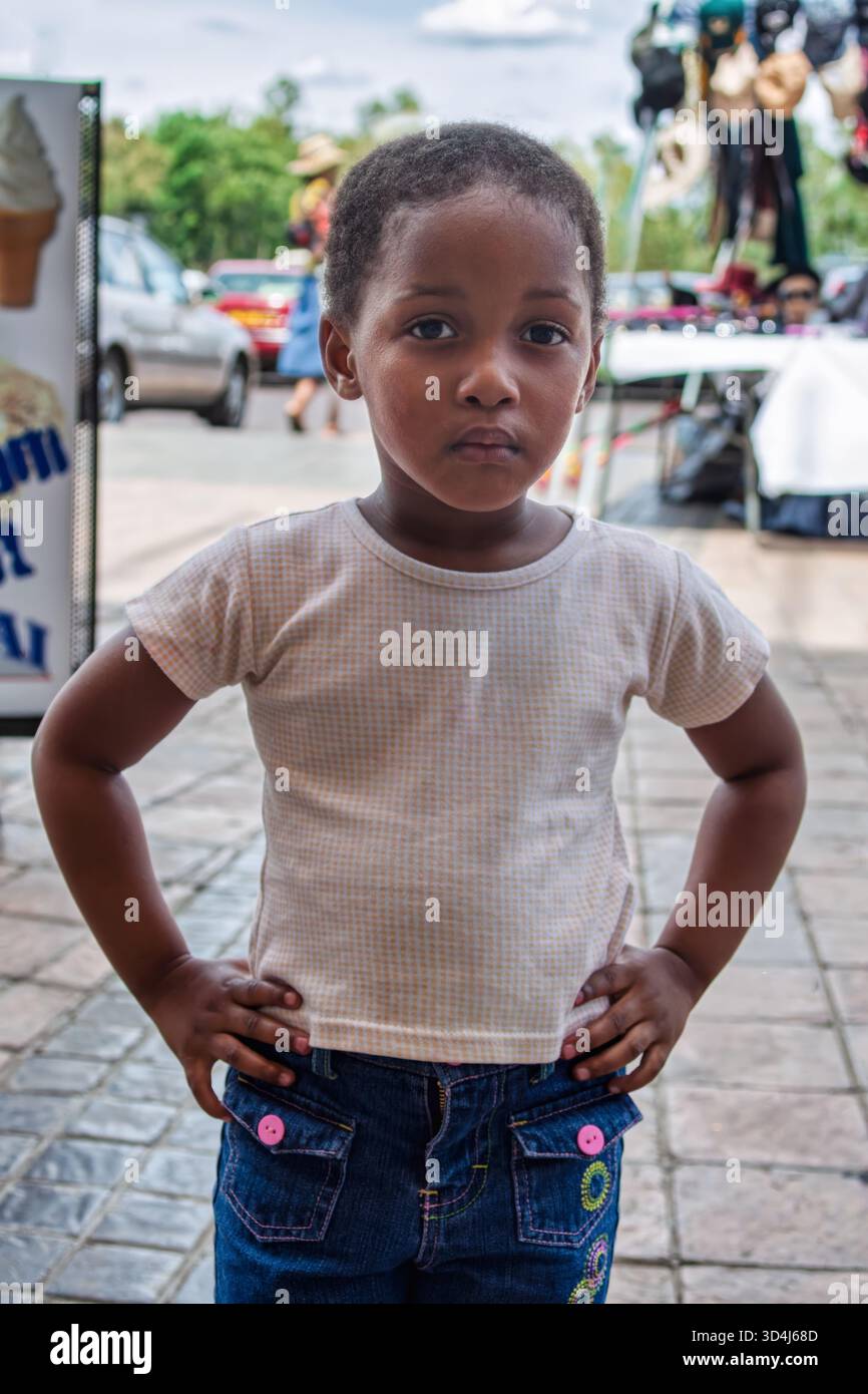 Porträt eines afrikanischen Mädchens, das auf der Straße steht, in einem Einkaufszentrum mit Autos parkt Stockfoto