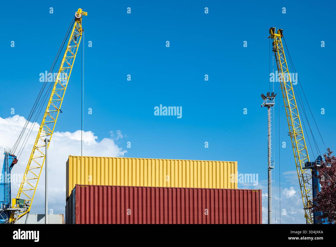 Be- und Entladen von Containern mit Kränen und Containertransportern am Hafen. Im Hafen gelagerte Seecontainer. Container-Frachtschiff mit Stockfoto
