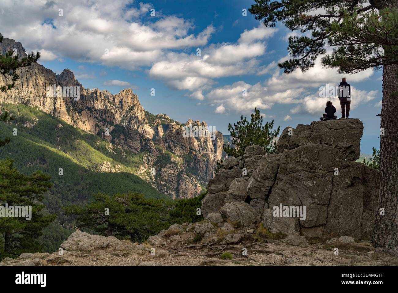 Touristen blicken vom Pass Col de Bavella auf den Gebirgszug der Bavella-Nadeln oder Aiguilles de Bavella, Korsika, Frankreich | Touristen auf Col de B Stockfoto