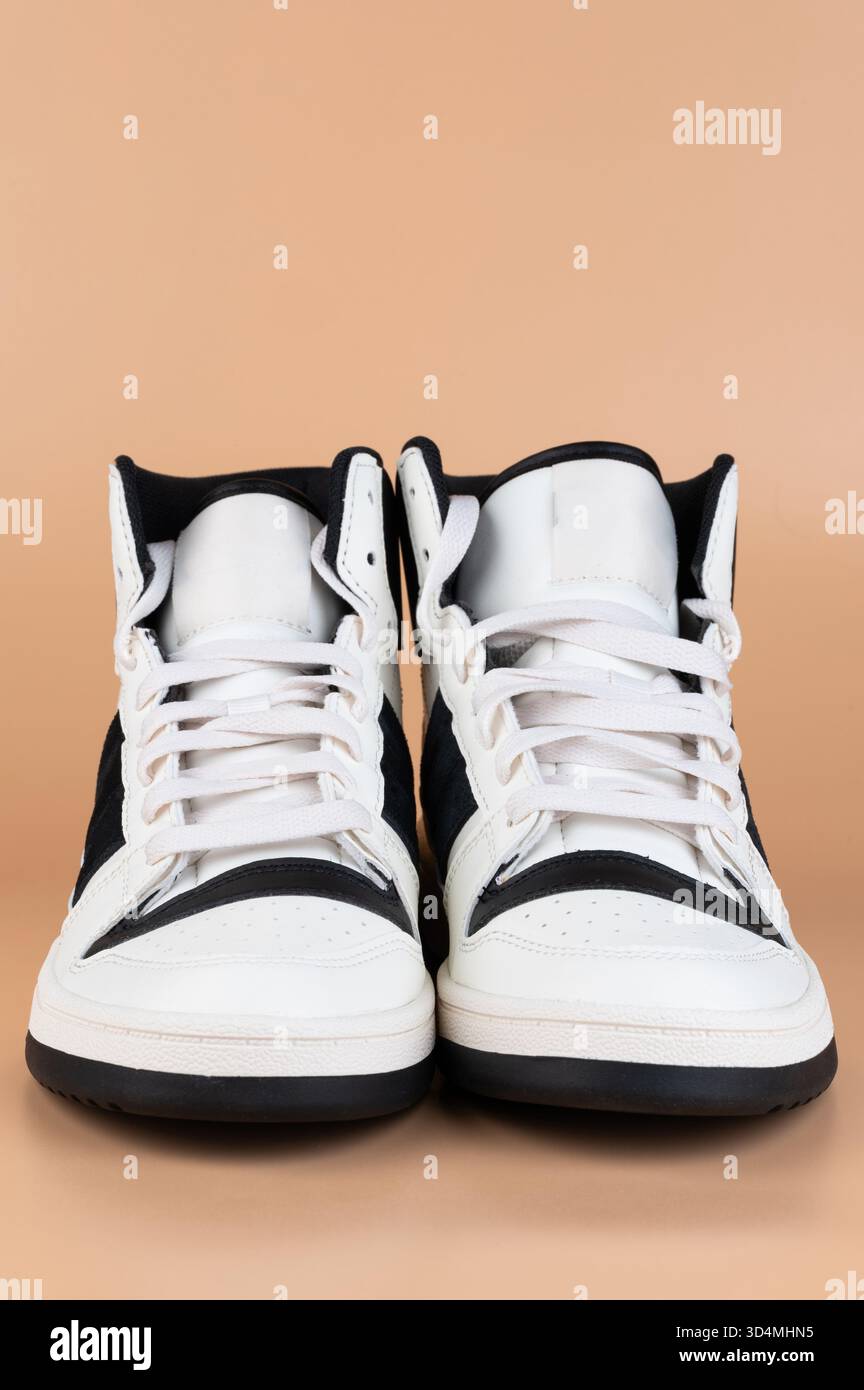 Ein Paar schwarze weiße Freizeitschuhe, Vorderansicht isoliert auf braunem Buckelboden Stockfoto