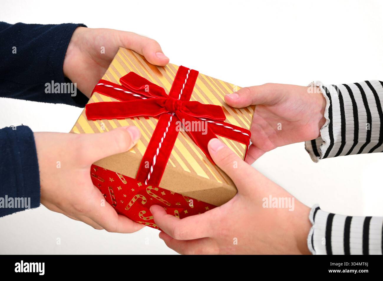 Kinderhände tauschen während der Weihnachtszeit ein verpacktes Geschenk aus. Stockfoto