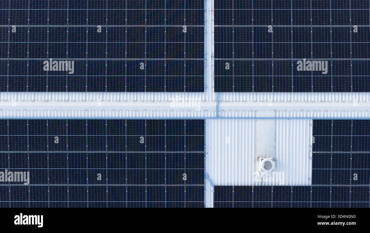 Top-down-Drohnenfoto von Solarenergie-Panels auf Industriedach, geometrisches Muster, das moderne grüne Technologie repräsentiert Stockfoto