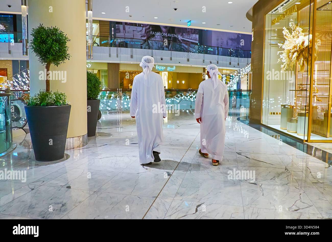 DUBAI, VAE - 7. MÄRZ 2020: Zwei Männer in traditioneller weißer arabischer Kleidung gehen am 7. März in Dubai durch die Vorhalle der Dubai Mall Stockfoto