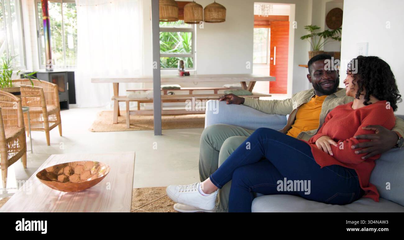 Sitzendes Paar, das sich zu Hause auf dem Sofa redet, Frau im Rostpullover, Kupferschüssel, Kopierraum Stockfoto