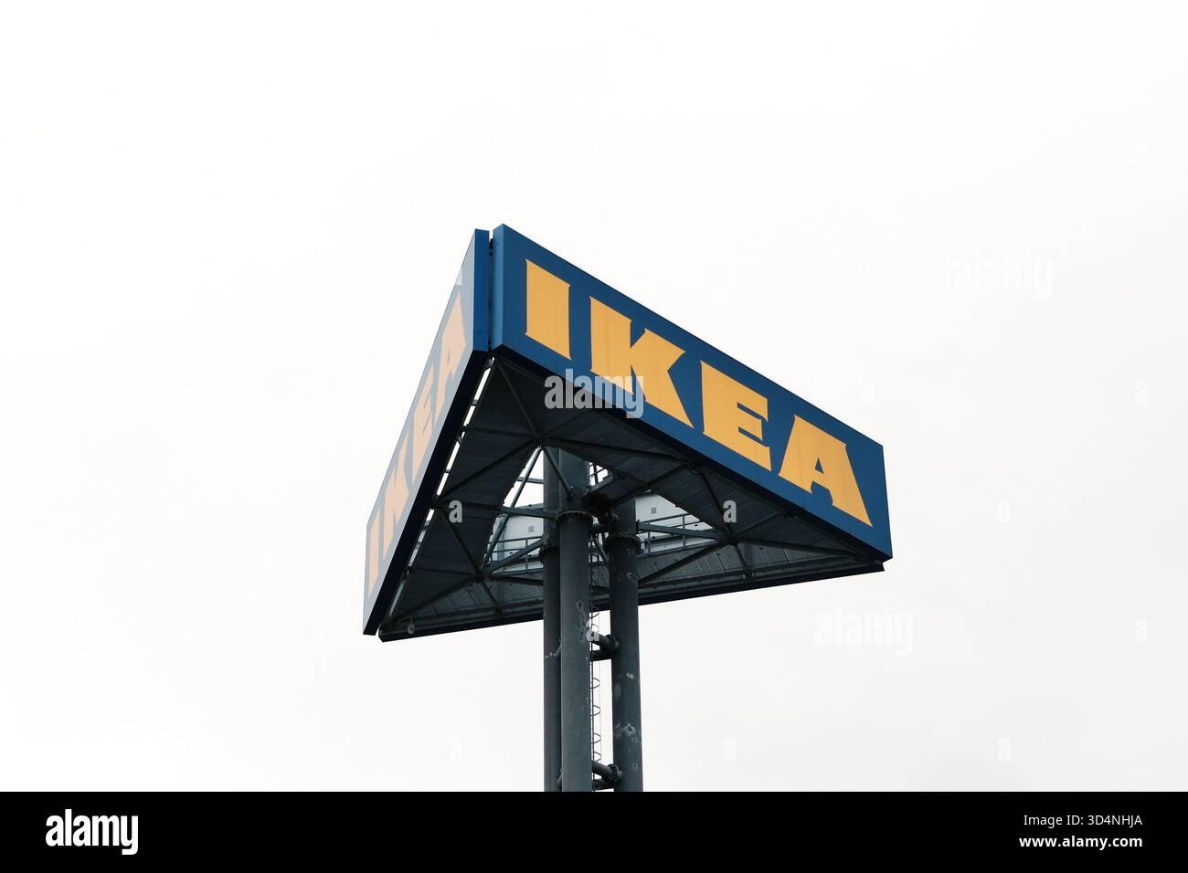Erhöhtes blaues und gelbes Ikea-Schild auf einem hohen Metallmast gegen bewölkten Himmel. Belgrad, Serbien - 7. November 2025. Stockfoto