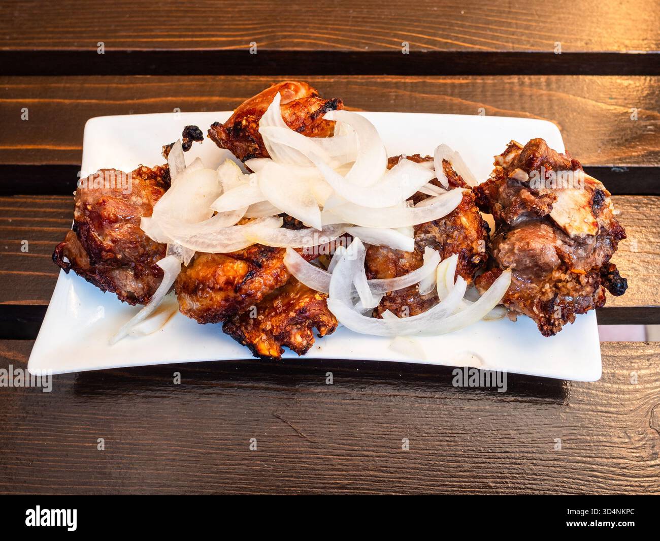 Georgianisches Lammschaschlik Mtsvadi auf weißem Teller auf Holztisch in einem lokalen Outdoor-Café in Borjomi Stadt, Georgia am Sommertag Stockfoto
