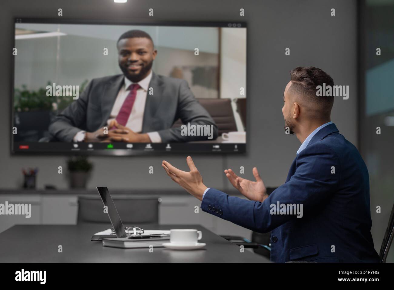 Ein junger Geschäftsmann aus dem Nahen Osten hält eine Videokonferenz mit einem afroamerikanischen CEO ab Stockfoto