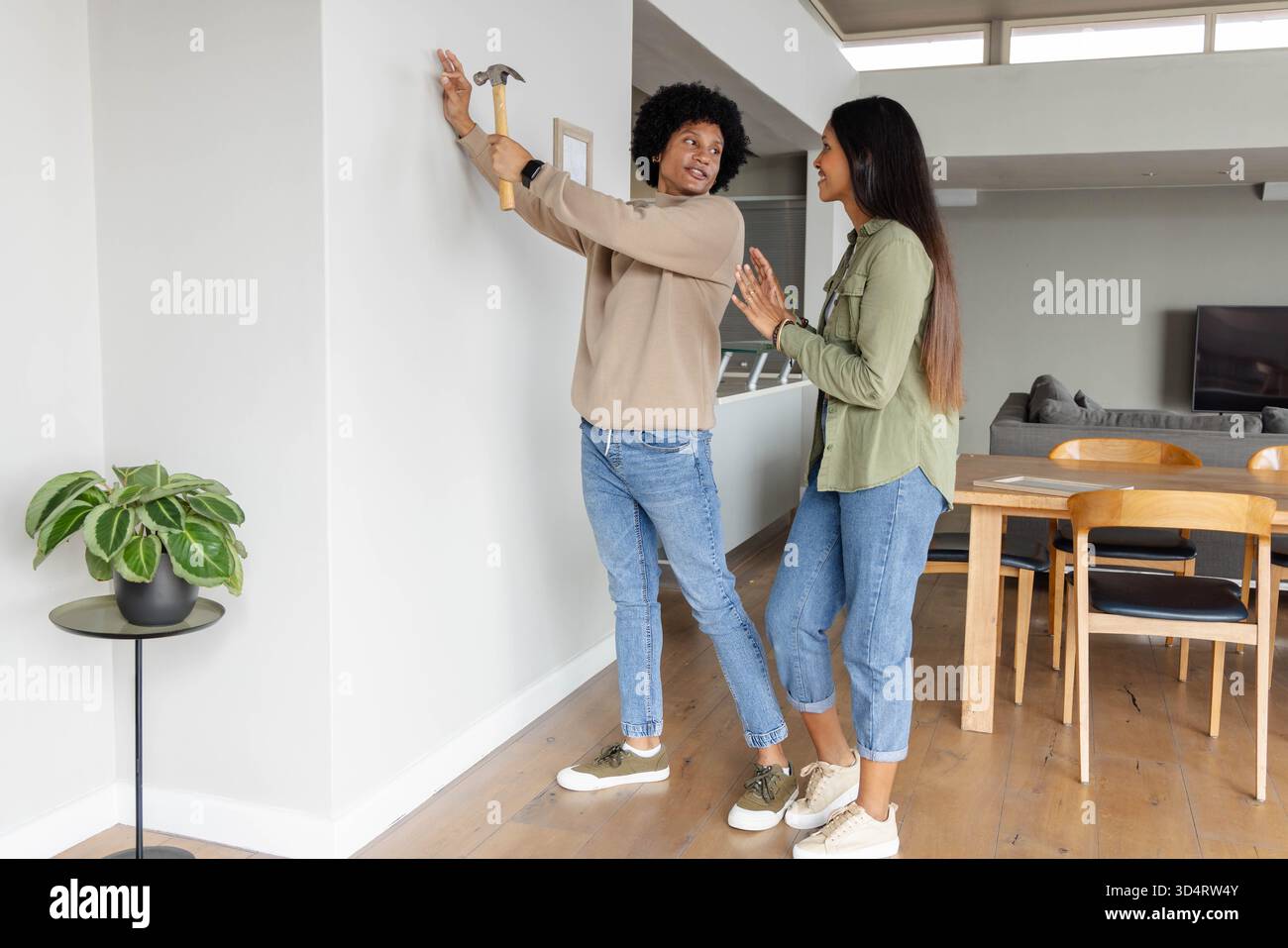 Vielfältiger Bilderrahmen für Paare an der Wand in offenem Wohnbereich, mit Hammer und Pflanze Stockfoto