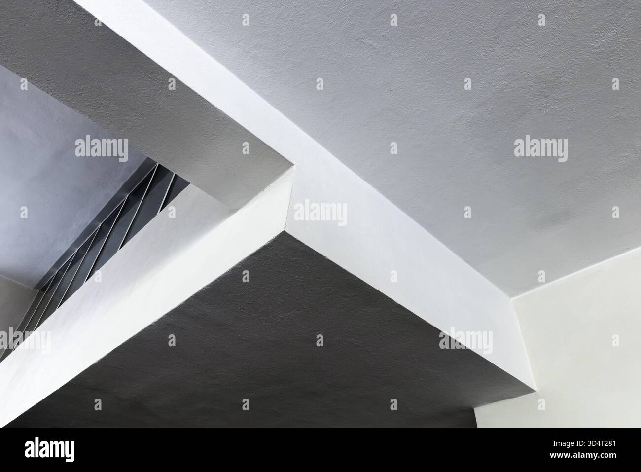 Eine eindrucksvolle Inneneinrichtung mit geometrischen Betonträgern und auffälligen sich kreuzenden Ebenen in weiß und Grau. Klare Linien erzeugen ein Gefühl von Tiefe, Mo Stockfoto