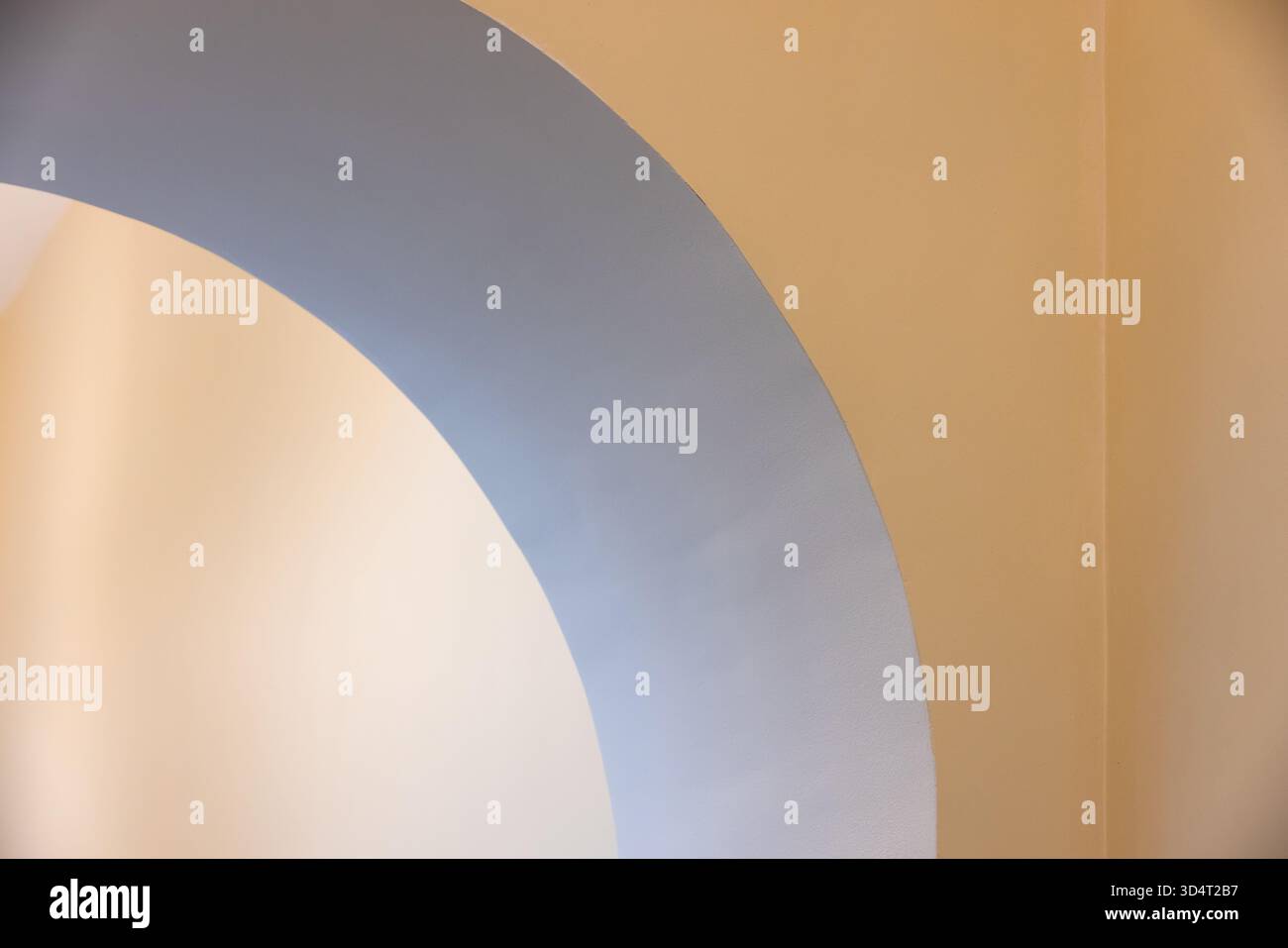 Ein glatter blauer Bogen zieht sich über eine warme, beige Wand und schafft eine ruhige, moderne Kulisse. Idealer abstrakter Hintergrund für Designprojekte, Fotografie Stockfoto