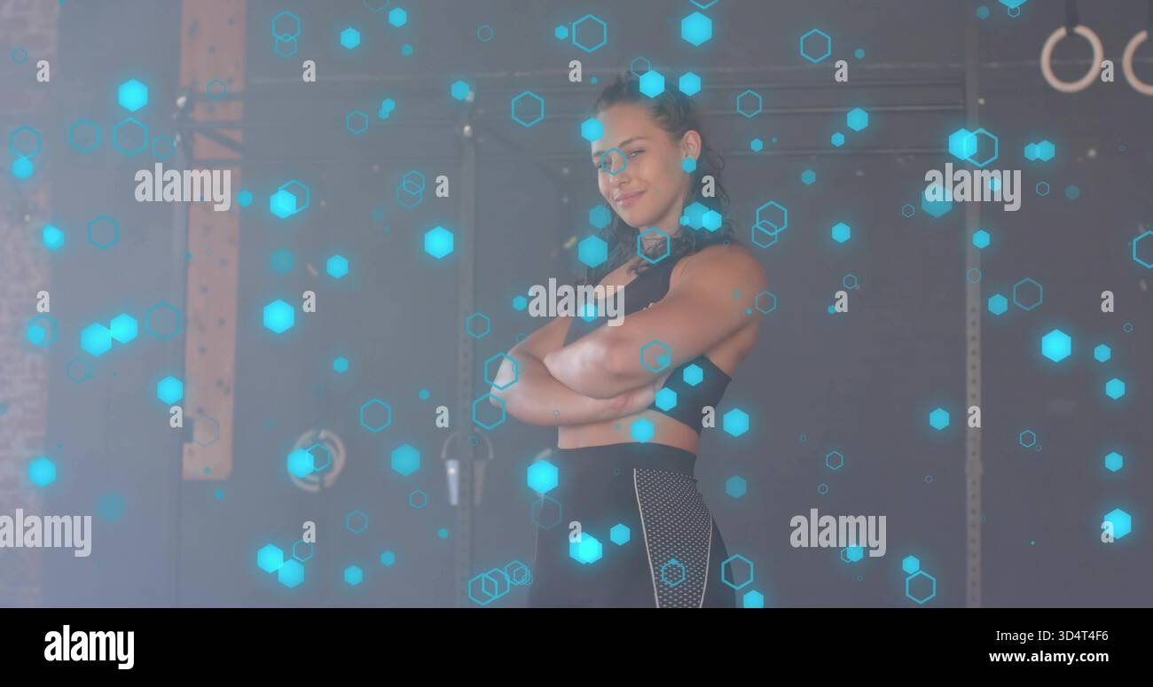 Stehende athletische Frau in schwarzer Sportbekleidung im Fitnessstudio, Turnringe, Zyan-Sechsecke Stockfoto