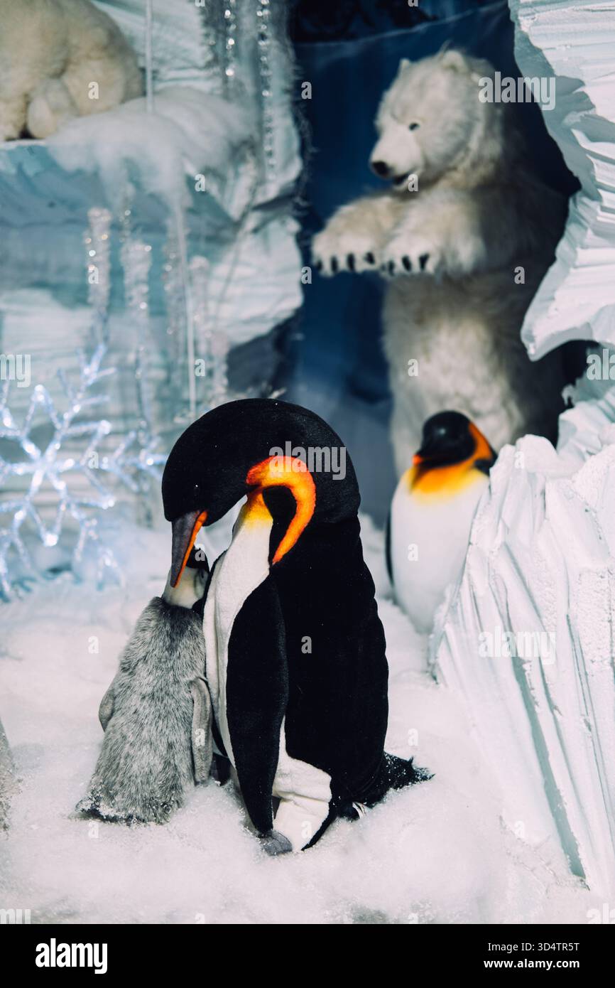 Üppige Kaiserpinguine und Eisbären in einem verschneiten Einzelhandelsgeschäft mit Eishöhle und Schneeflockendekor. Winterthema mit Tierwelt. Warschau, Polen Stockfoto