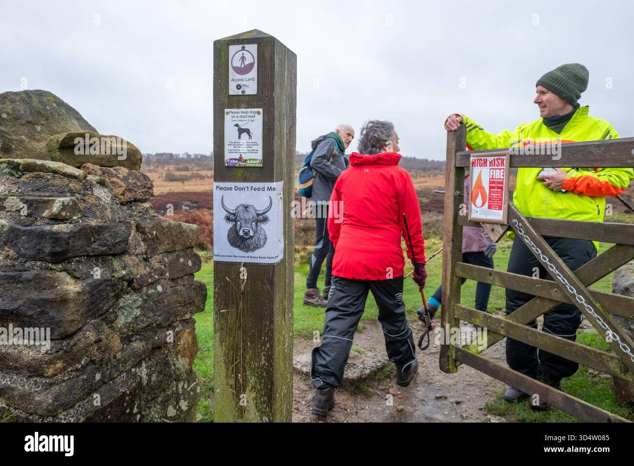 Eine Gruppe von Wanderern durchquert ein hölzernes Fußpfadttor und geht in Richtung Blackstone Edge im Derbyshire Peak District nahe Baslow. Stockfoto