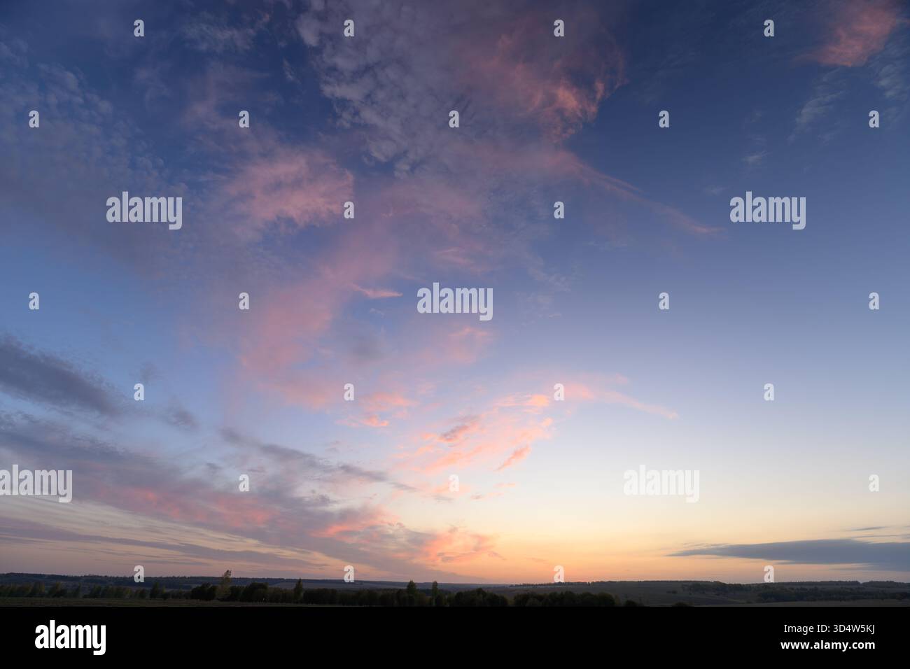 Ein atemberaubend schöner Sonnenuntergang zeigt leuchtend rosa Wolken, die das weiche, verblassende Licht vor einem friedlichen Horizont reflektieren Stockfoto
