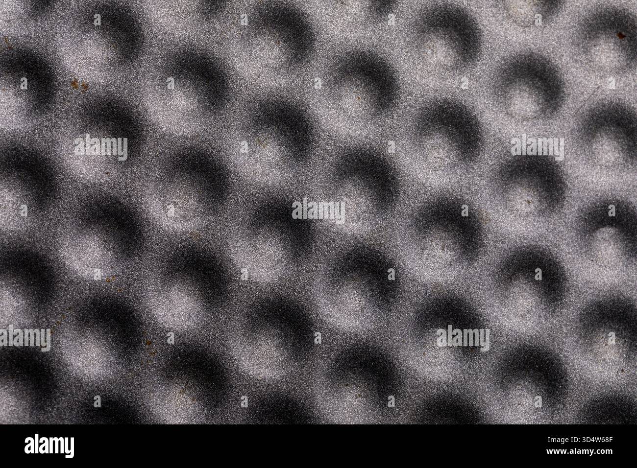 Nahaufnahme einer grauen Oberfläche mit sich wiederholenden kreisförmigen Einkerbungen, ideal für Hintergründe, Design und industrielle Konzepte. Stockfoto