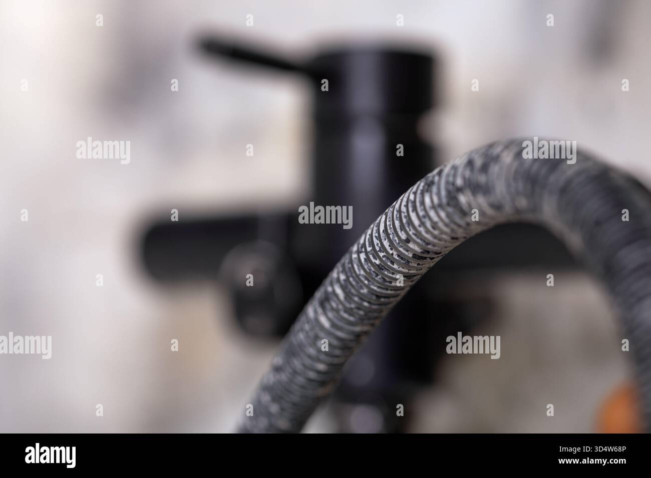 Detaillierte Nahaufnahme eines texturierten Industrieschlauchs mit verschwommenem Ventilhintergrund, die langlebige Materialien für Sanitär-, Konstruktions- oder Konstruktionstechnik hervorhebt Stockfoto