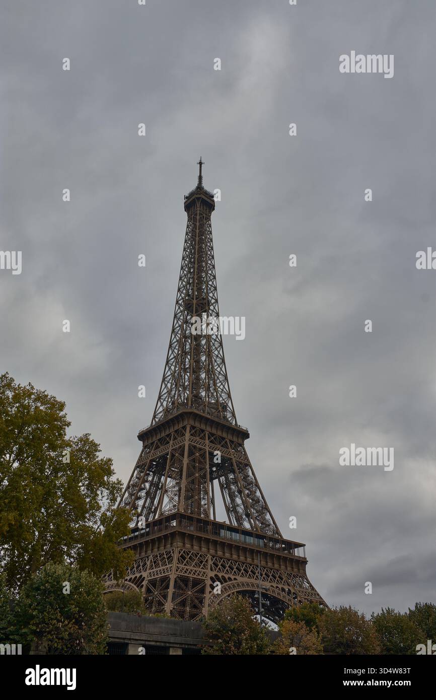 Der Eiffelturm erhebt sich eindrucksvoll in Paris unter einem bewölkten Himmel und unterstreicht seine schmiedeeiserne Struktur als Erbe der Weltausstellung 1889. Das Grau Stockfoto