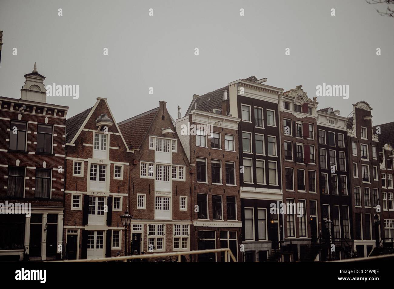 Nebeliger Morgen in Amsterdam mit Kanalhäusern und historischen Fassaden, die sich im ruhigen Wasser spiegeln, stimmungsvolle Stadtlandschaft Stockfoto