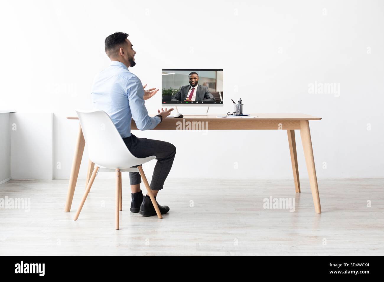 Arabischer Mann, der während der Arbeit am Büroschalter Videoanrufe mit Kollegen führt Stockfoto