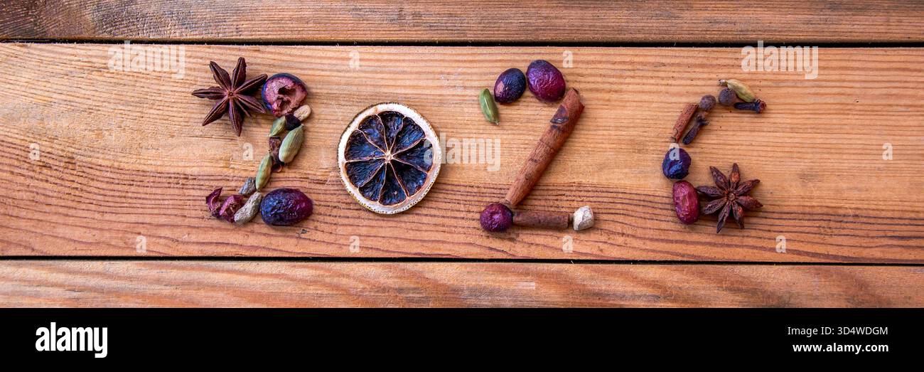 2026 geschrieben mit Weihnachtsgewürzen und getrockneten Lebensmitteln auf hölzernem Hintergrund, Neujahrsfahnenbanner Stockfoto