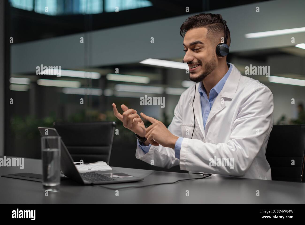 Gutaussehender junger Wissenschaftler aus dem Nahen Osten, der sich im Videochat in modernem Labor engagiert Stockfoto