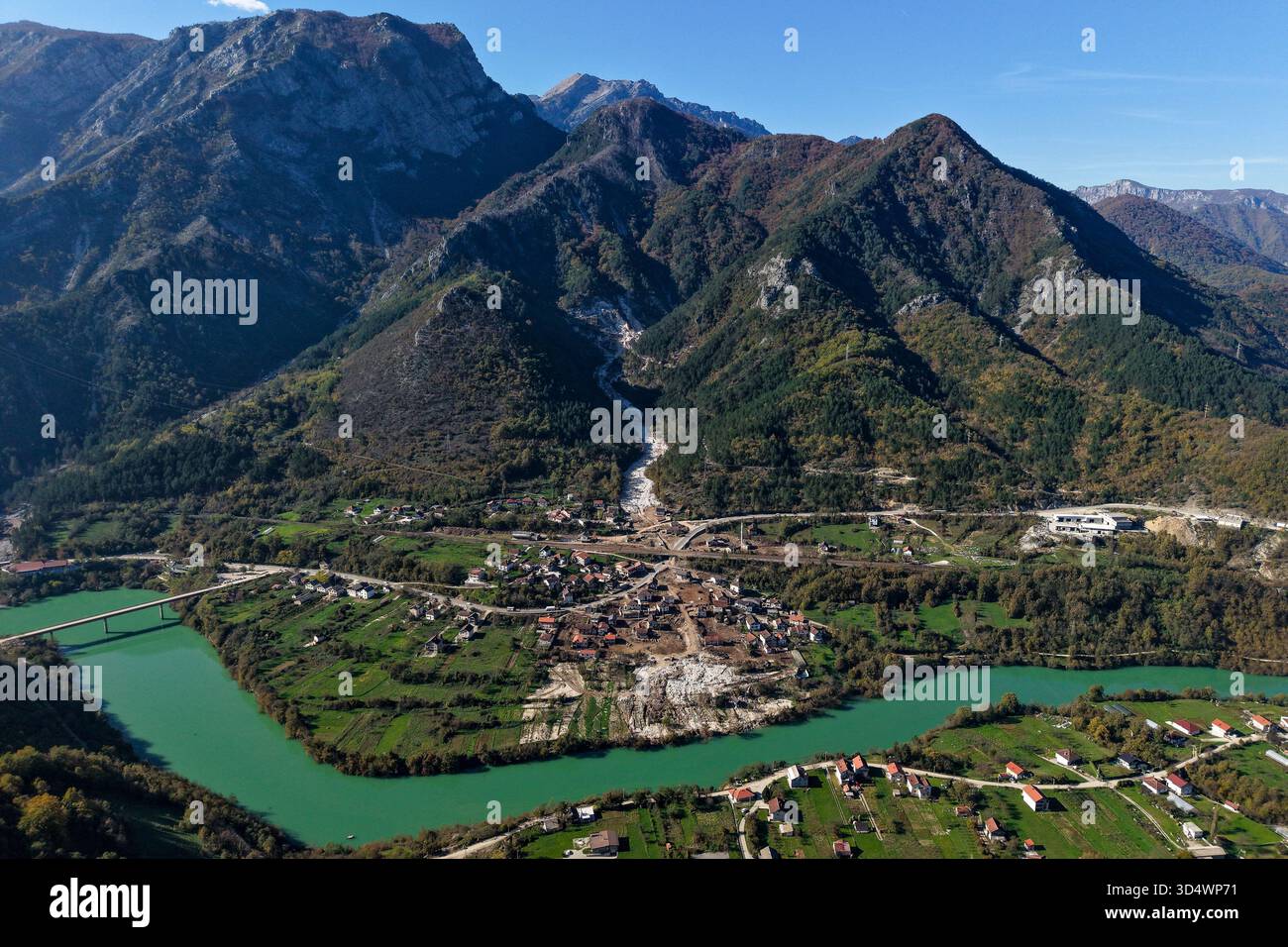 Von der Vogelperspektive auf das smaragdgrüne Flusswasser umgibt eine kleine Stadt am Fuße der majestätischen Berge Donja Jablanica, Föderation von Bosnien und Herzegowina Stockfoto
