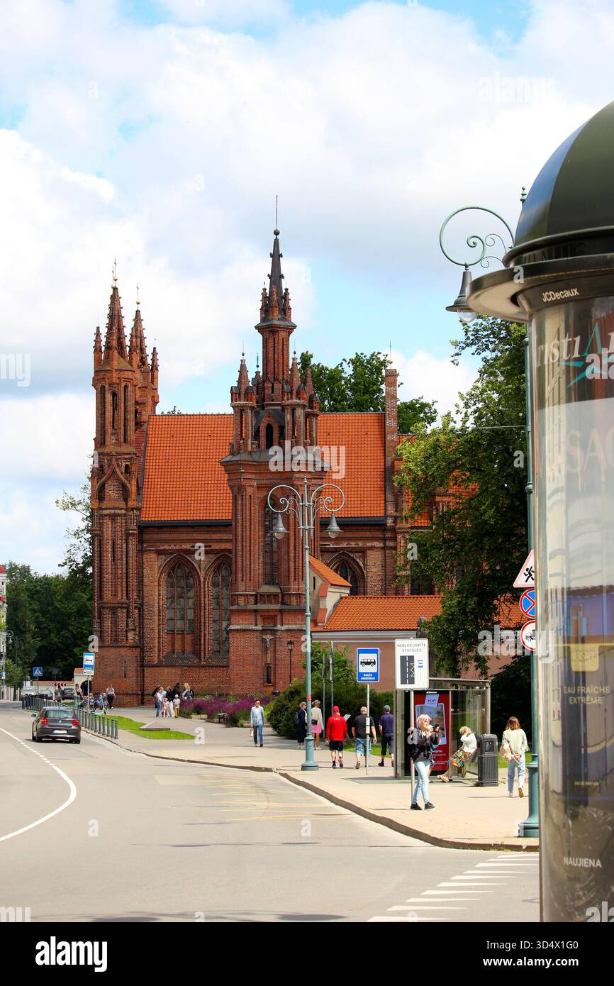Annenkirche in Vilnius, Litauen, mit Touristen, die an einem sonnigen Sommertag auf der Straße spazieren gehen. Historische gotische Architektur und Stadtleben in t Stockfoto