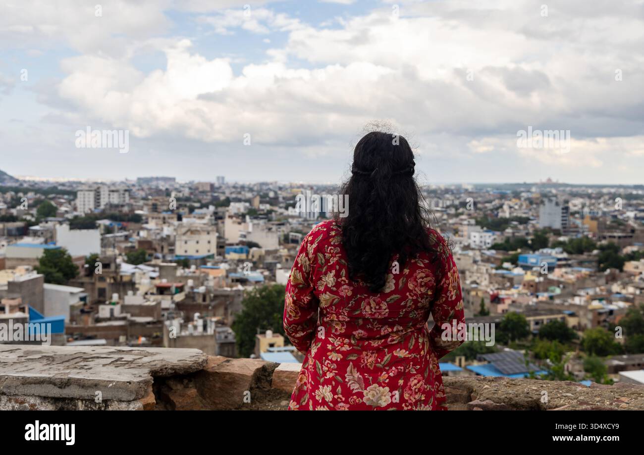 alleinreisender mit Blick auf die überfüllte Skyline der indischen Stadt während des Monsuns Stockfoto