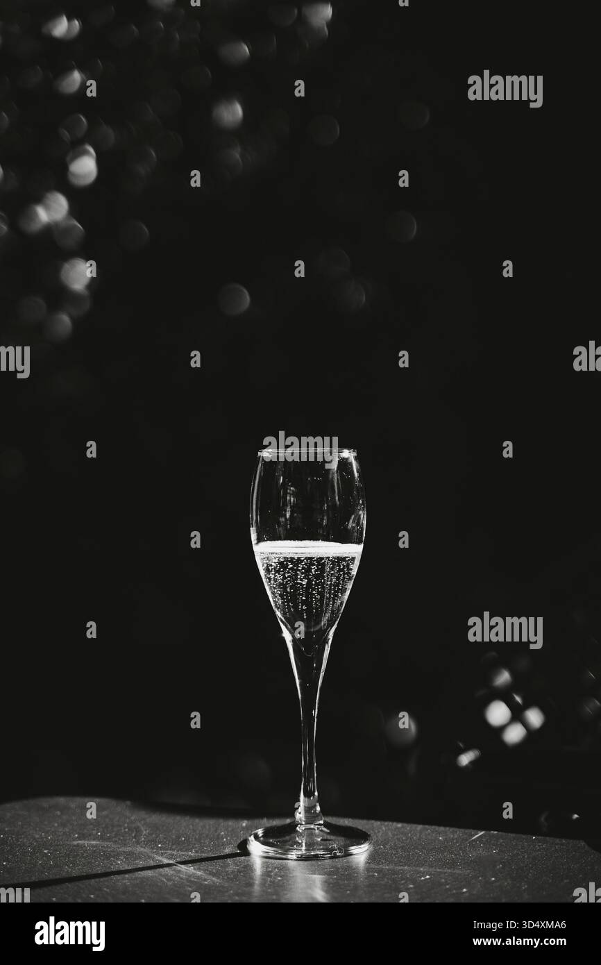 Elegantes Schwarz-weiß-Foto eines Champagnerglases mit glitzernden Blasen im Inneren. Die minimalistische Komposition betont das Glas Stockfoto