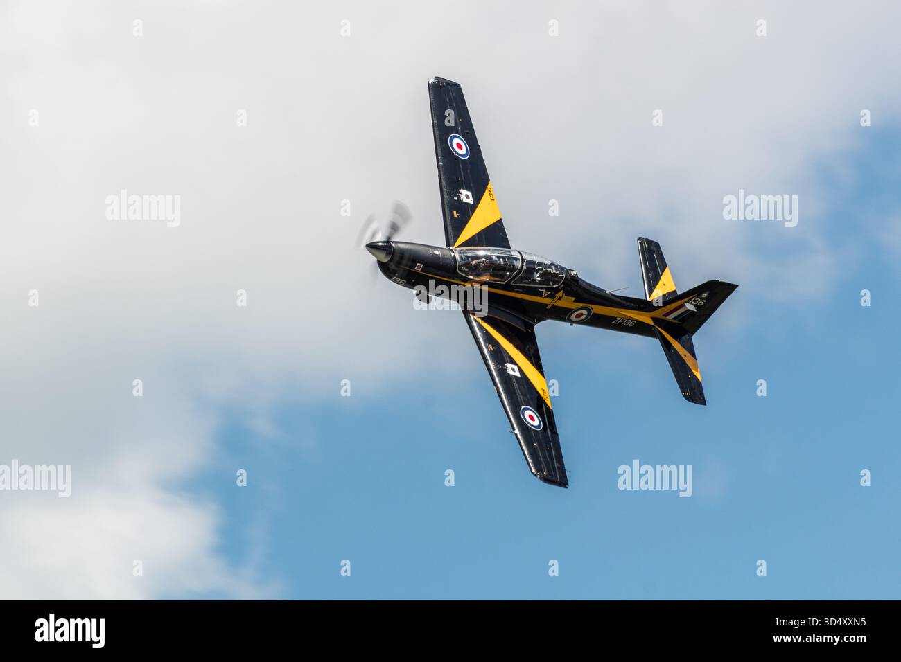 Royal Air Force kurze Tucano T1 Militärtrainingsflugzeuge im Flug, teilweise bewölkter Himmel, Durchführung eines Bankmanövers mit Propellerdrehung. Stockfoto