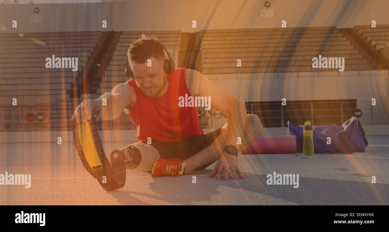 Dehnender Mann mit Klinge, rotes Oberteil und schwarze Shorts auf der Schiene, mit Kopfhörern Stockfoto