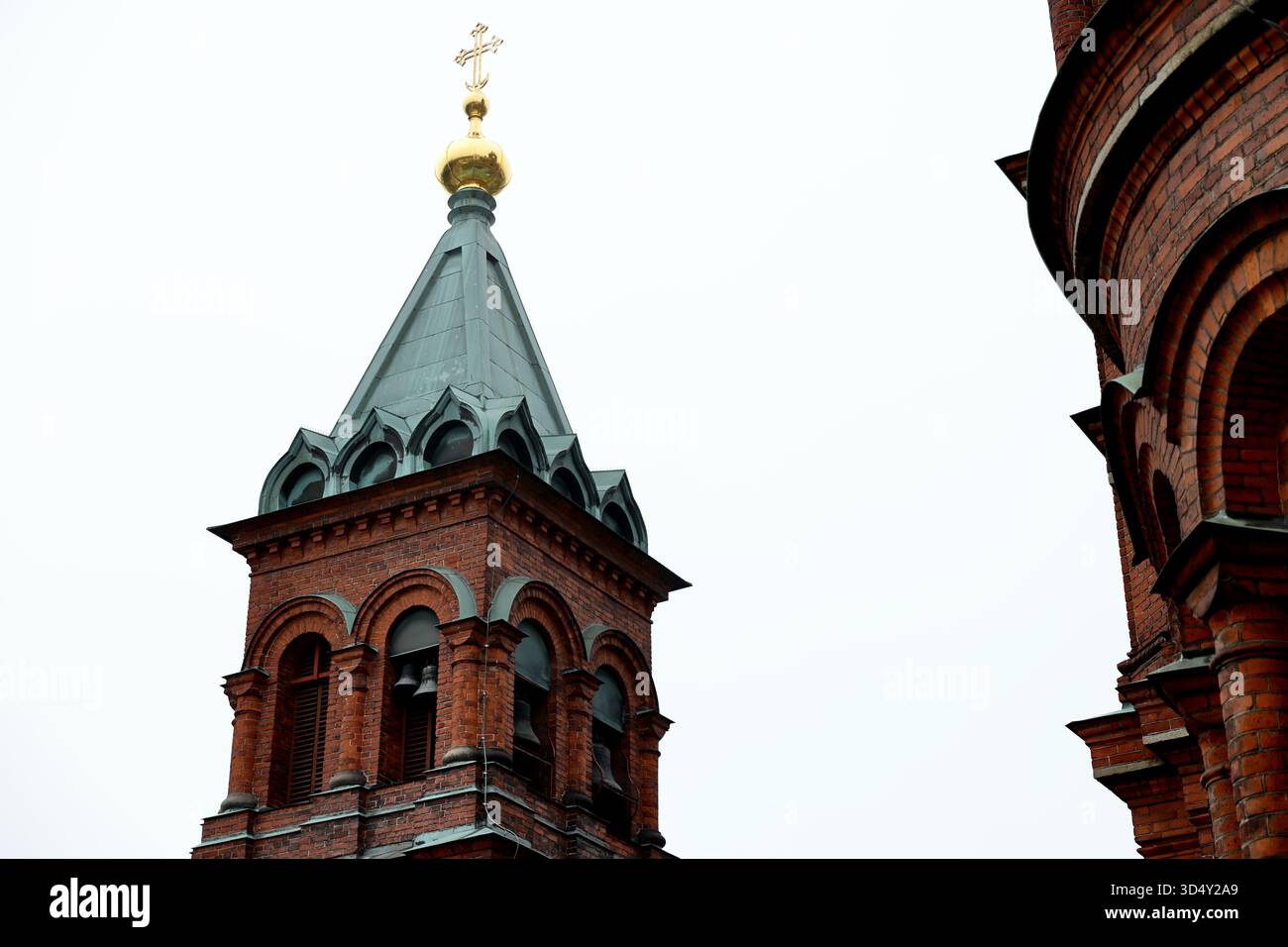 Glockenturm der Uspenski-Kathedrale mit Kupferturm und Glocken, Helsinki, Finnland, neben der Ziegelfassade gesehen, oben vor einem weißen Himmel fotografiert. Stockfoto